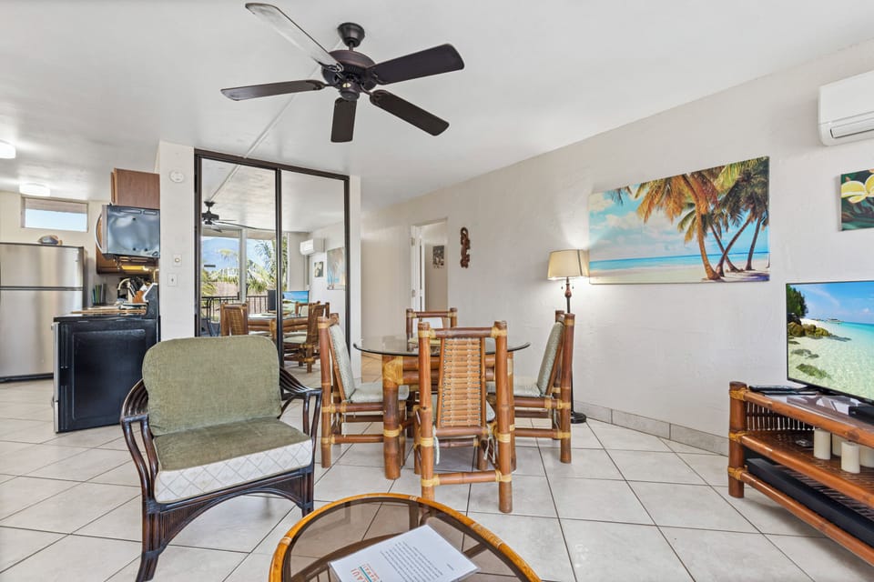 Relax in your bright, breezy living space with tropical island artwork, ceiling fan, and open layout connecting you to dining and kitchen areas—all with ocean views from your balcony.