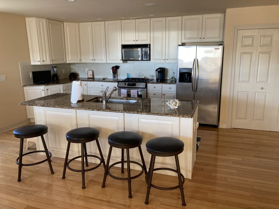 View of kitchen , center island with stools , island with modern appliance’s