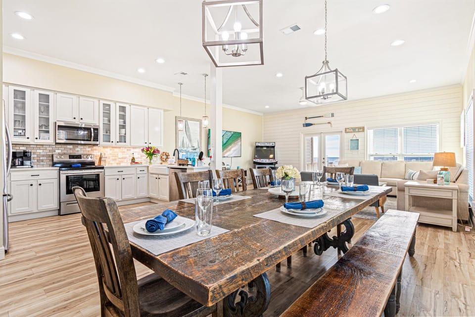 A long dining room table that seats 10 in style! This spacious dining area is perfect for hosting large gatherings while enjoying delicious meals together. With ample seating, beautiful views, and a beachy vibe.