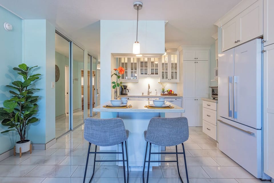 Gather at this bright breakfast bar where coastal blues meet crisp whites. Your morning coffee awaits, with every appliance and plate right within reach for an easy, breezy start to your day.