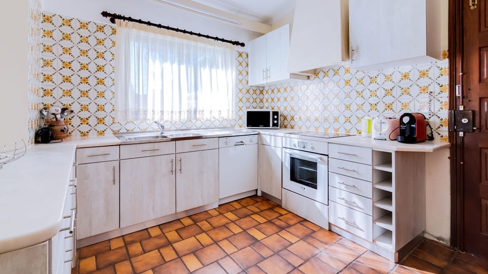 A fully equipped kitchen with all appliances like oven, stove, microwave, coffee machine, washing machine, and toaster