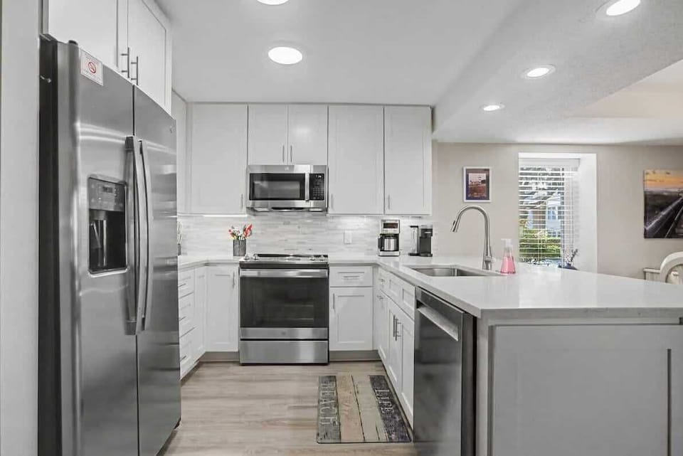 Your fully equipped modern kitchen features sleek white cabinets, stainless steel appliances, and plenty of counter space for preparing meals during your stay.