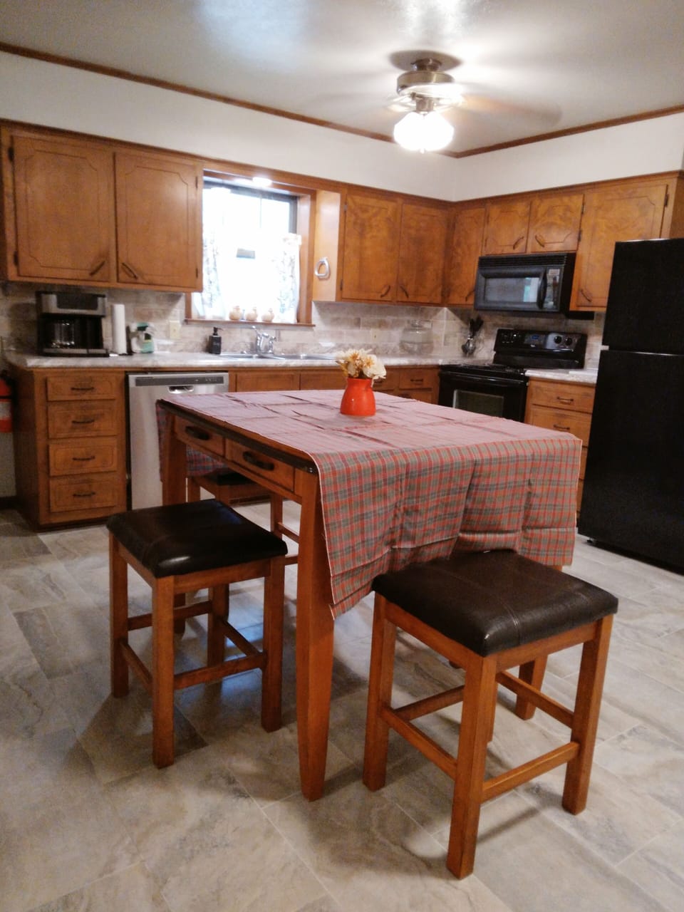 Kitchen w table and 4 chairs, fridge, microwave, stove, dishwasher, and dishes.