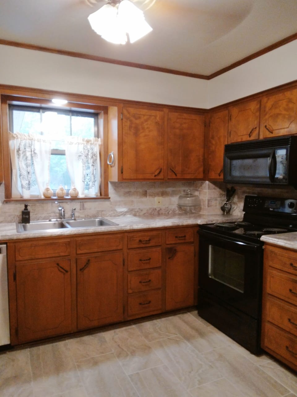 Kitchen w table and 4 chairs, fridge, microwave, stove, dishwasher, and dishes.