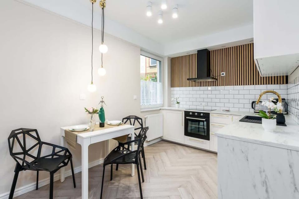 A dining and kitchen area with a table and chairs, illuminated by soft pendant lighting.
