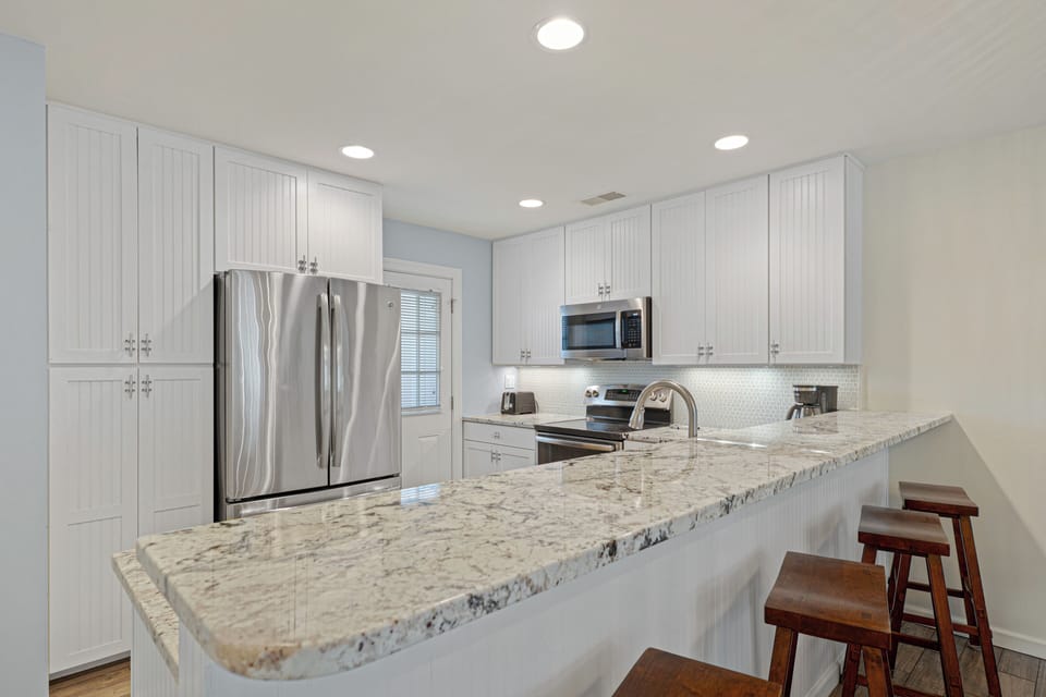 The long breakfast bar doubles as a natural gathering spot, making this kitchen just as suited for casual mornings as it is for hosting friends and family.