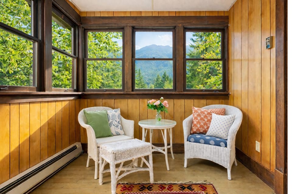 Unwind in your cozy sunroom with mountain views, where wicker chairs and colorful cushions create the perfect reading nook.