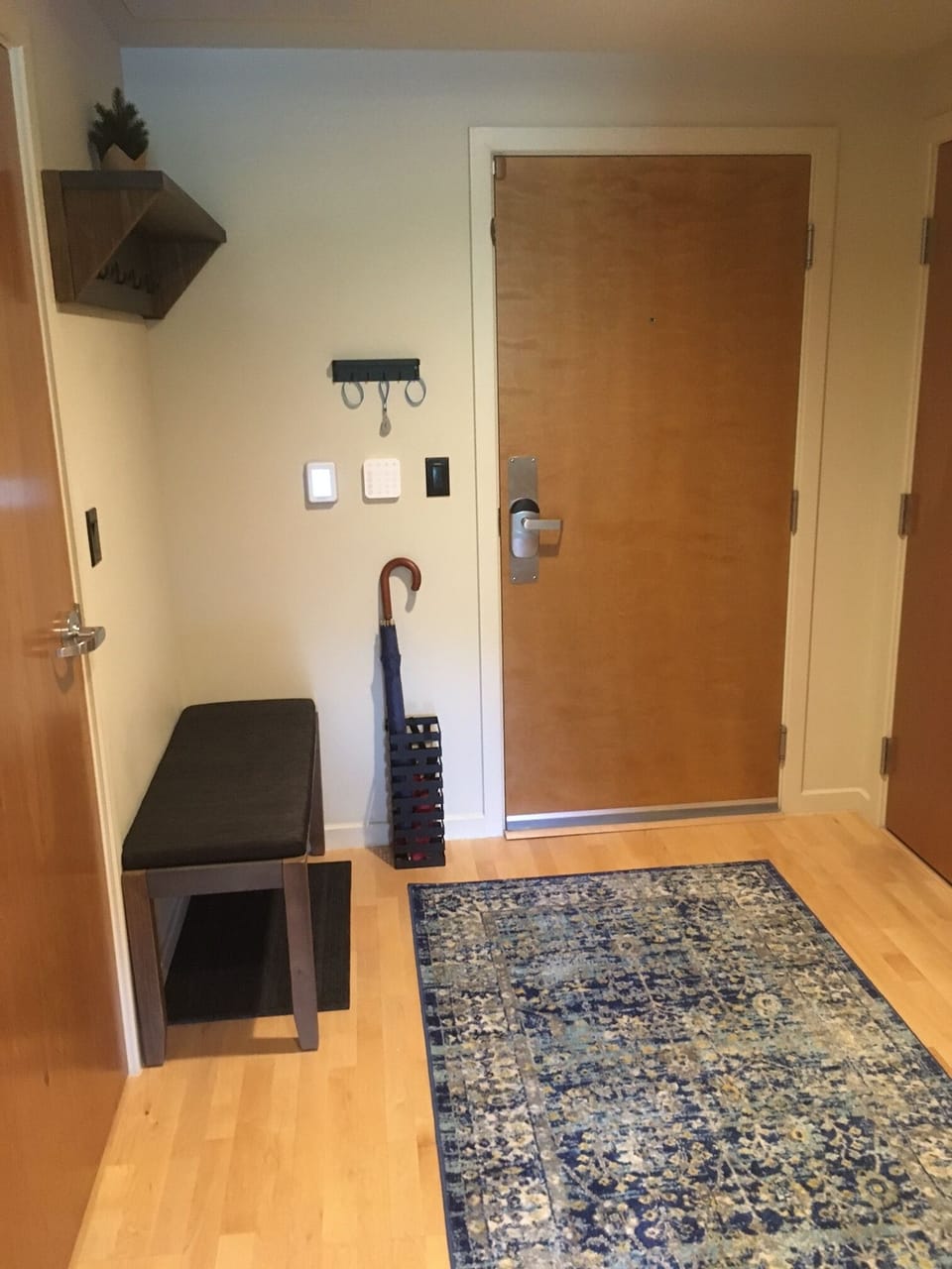 Entry foyer with bench, key hook, coat rack, and umbrellas