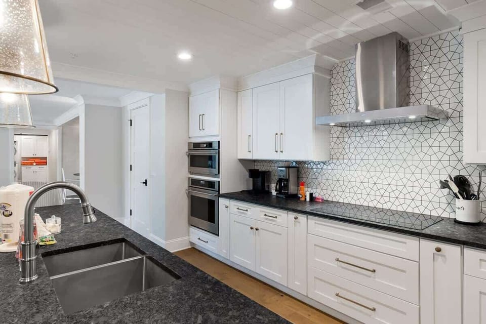 Modern kitchen with white cabinetry, geometric tile backsplash, and stainless steel appliances
