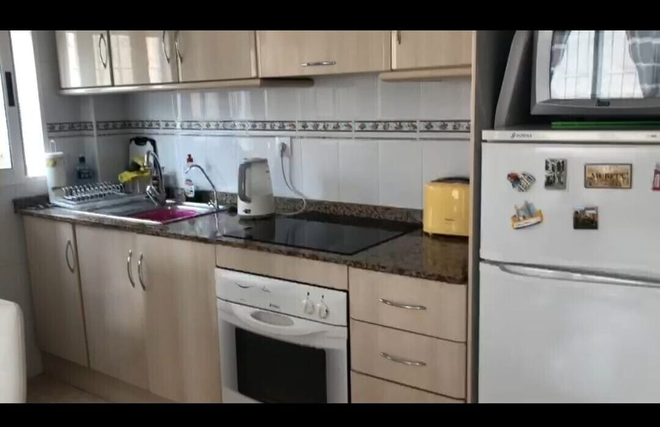 Kitchen with oven, hob, fridge and microwave.