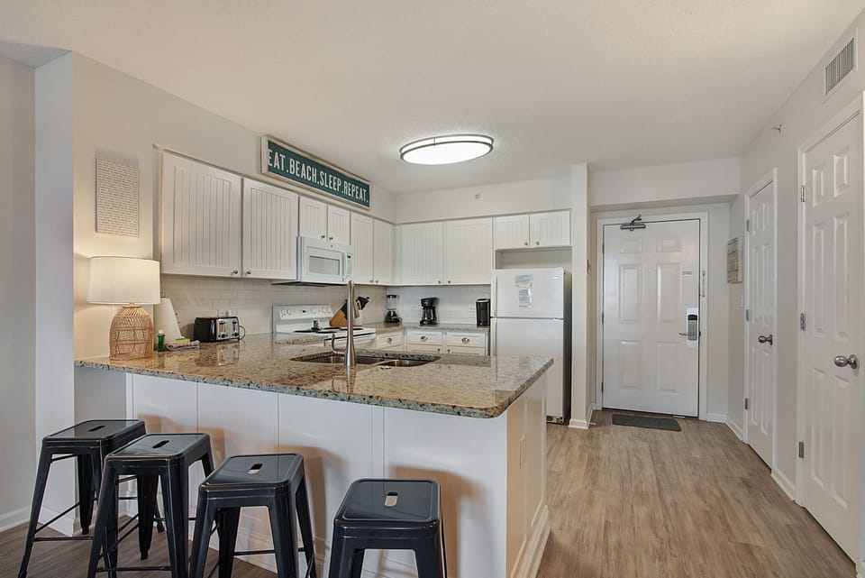 Your fully-equipped kitchen invites morning coffee conversations at the granite breakfast bar, with modern appliances ready for home-cooked meals.
