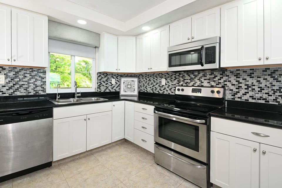 You'll love cooking in this modern kitchen with sleek granite counters, stainless steel appliances, and charming mosaic tile backsplash.
