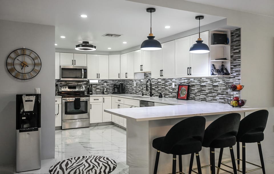 Cook your favorite meals in this modern kitchen with sleek white cabinets, stylish pendant lighting, and spacious island seating.