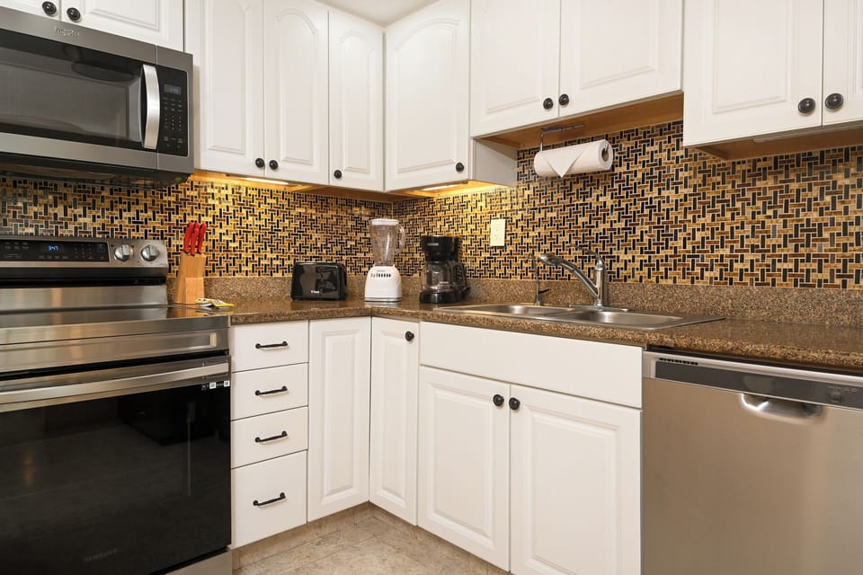 Your fully equipped kitchen features granite countertops, mosaic backsplash, and stainless steel appliances perfect for preparing home-cooked meals during your stay.