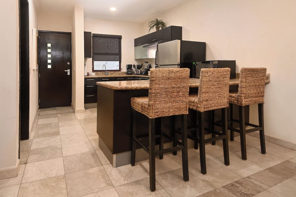 Your sleek kitchen features granite countertops, stainless steel appliances, and comfortable wicker bar stools for casual dining and morning coffee.