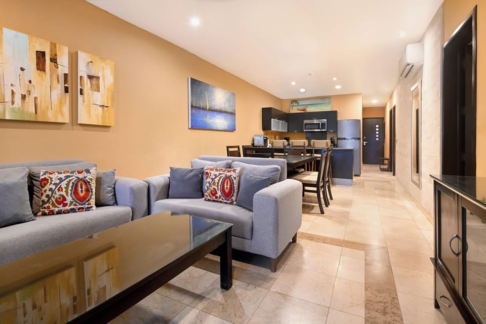 Step into your spacious open-plan living area where comfort meets style. Sink into plush sofas, enjoy meals at the dining table, and prepare snacks in the modern kitchen—all bathed in warm, welcoming light.