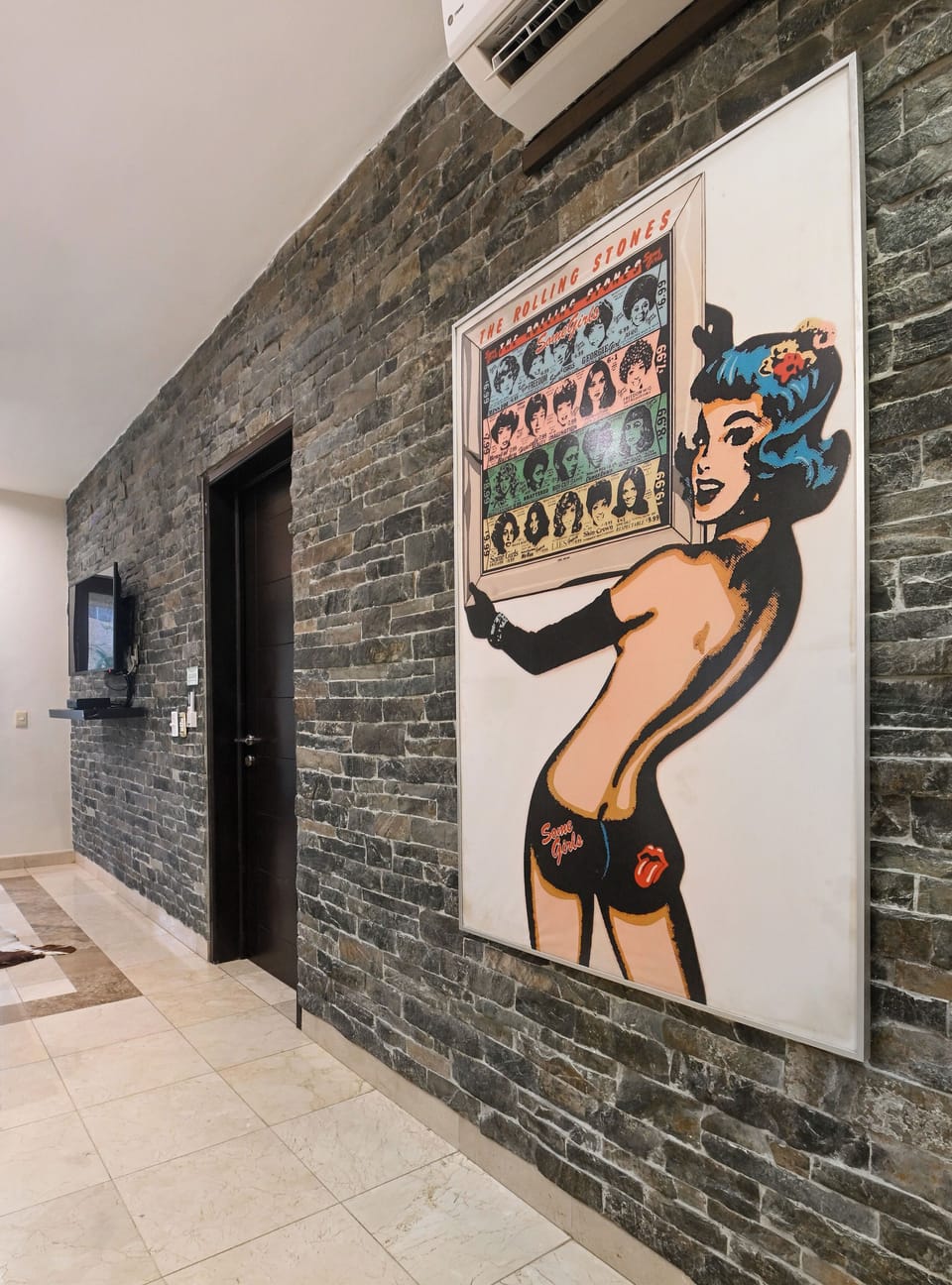 A striking interior hallway features exposed brick, bold pop art, and modern air conditioning—a stylish blend of urban character and comfort to welcome you in.