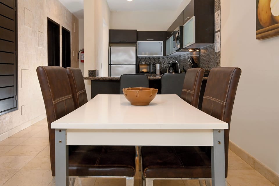 Gather around your modern dining table in this sleek open-plan space, where stainless steel appliances and stylish dark cabinetry make meal prep a breeze.