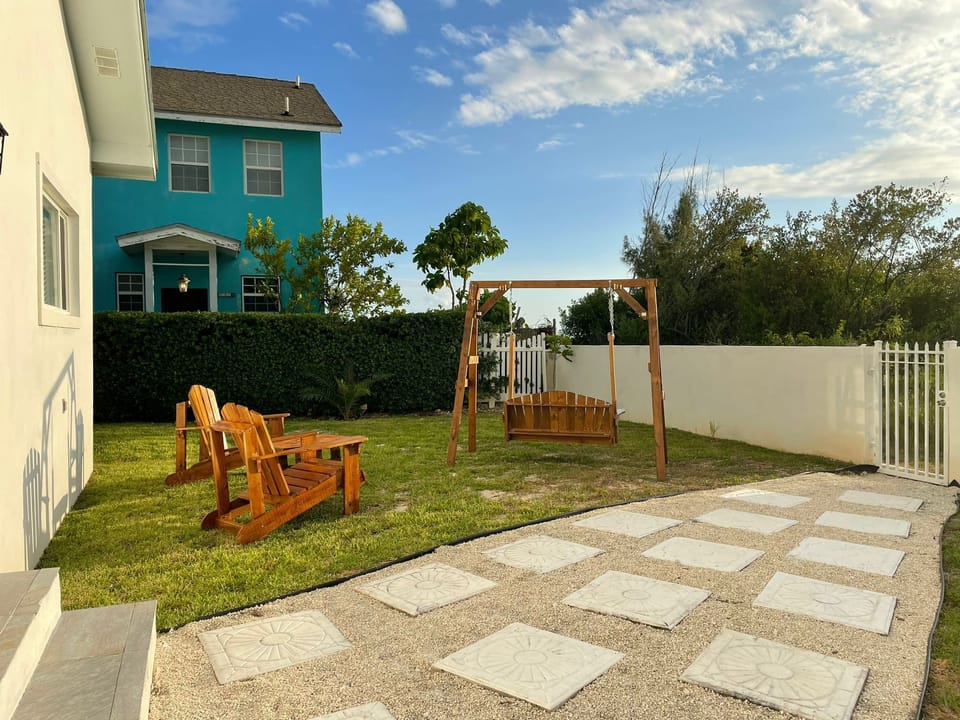 Spacious backyard with wooden chairs, a table & a swing