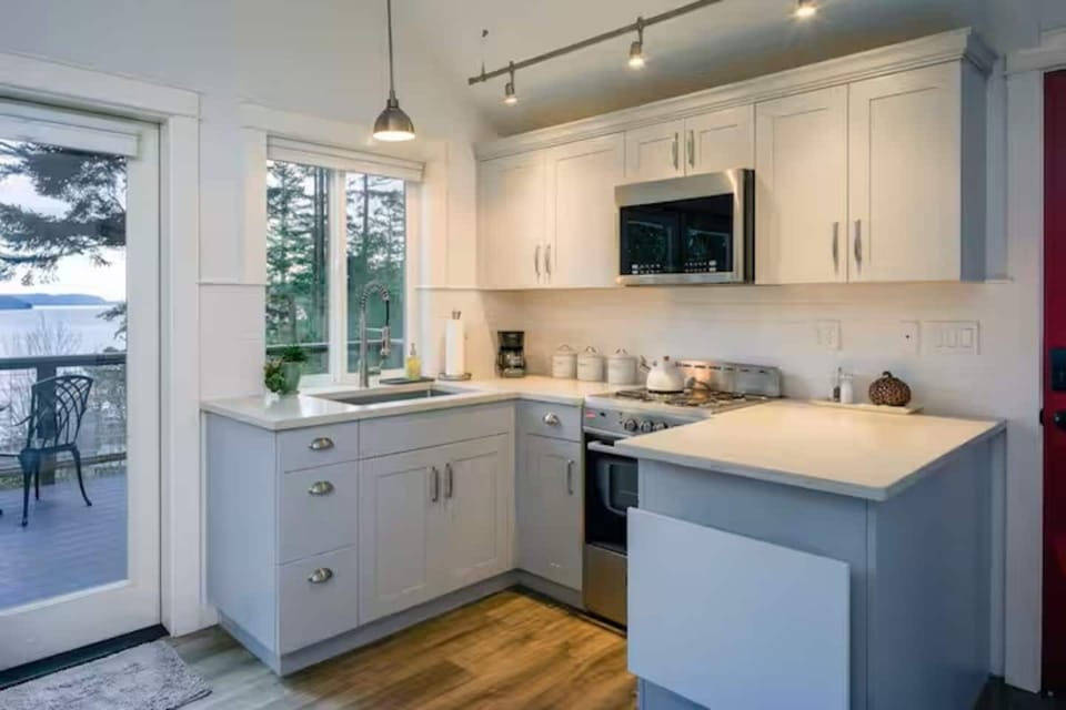 Modern kitchen with electric stovetop and oven, Blomberg stackable washer and dryer.