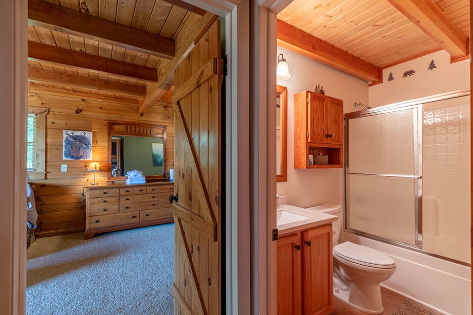 A charming barn door connects the bedroom and bath, keeping that cozy log cabin feel throughout Whispering Ridge Retreat.