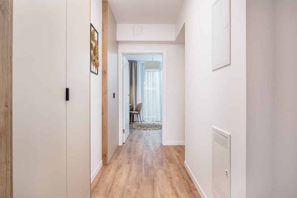 Modern, bright bathroom with imitation marble tiles. The white washbasin above which hangs a decorative round mirror sits on a wooden countertop.