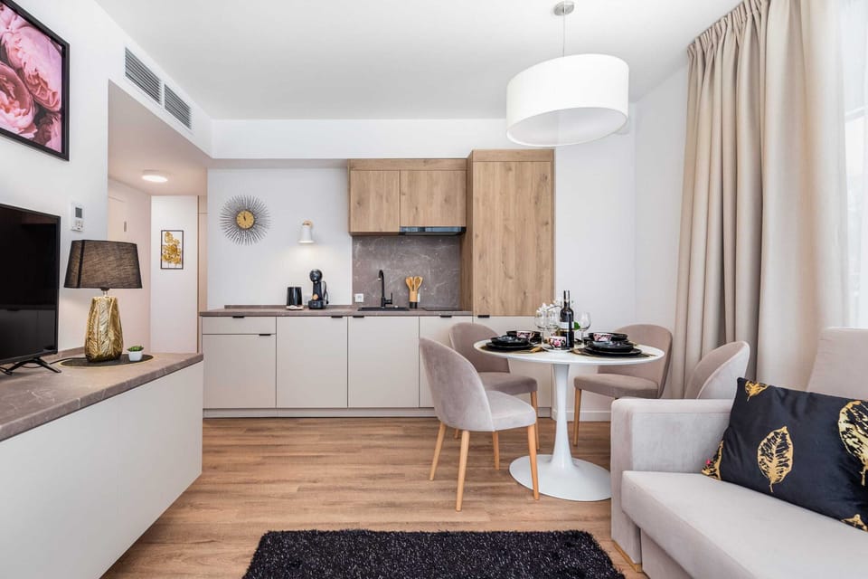 A wider perspective of a cosy and stylish space that combines a seating area with a dining area. In the background is the kitchenette.