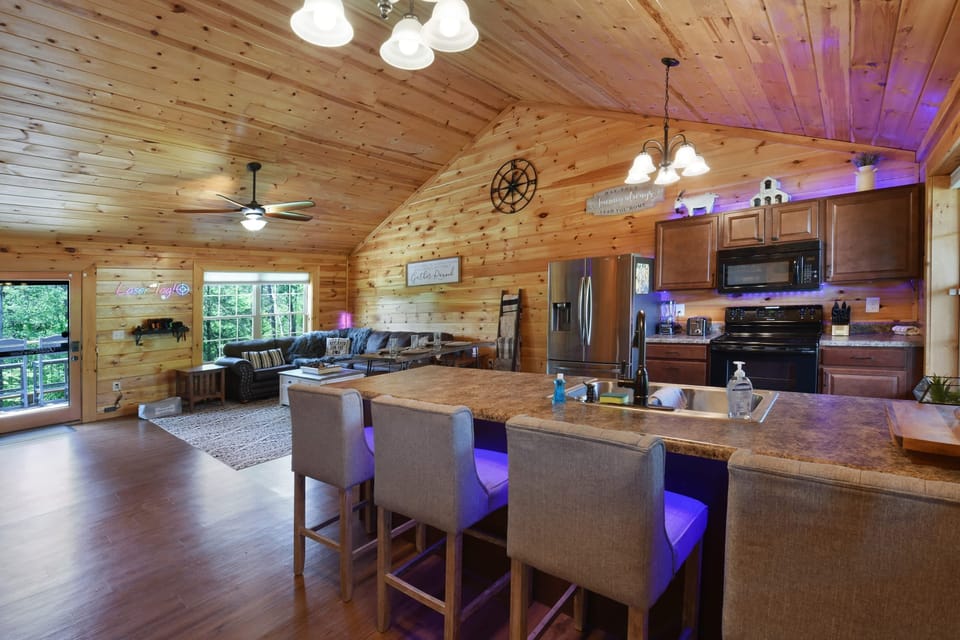 Open-concept rustic kitchen and living area with vaulted wood ceilings and modern appliances.