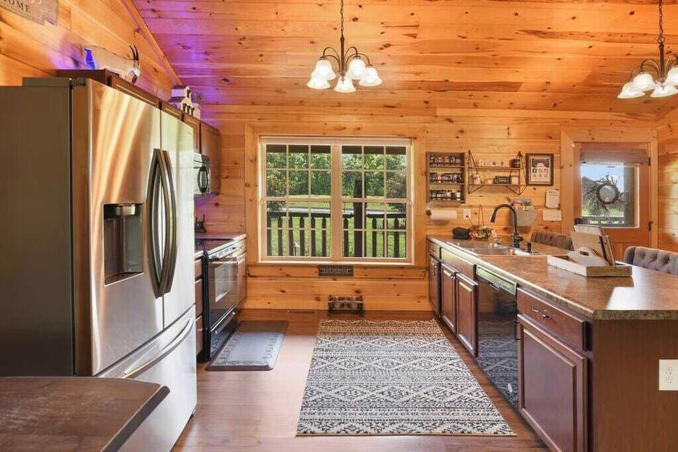Rustic kitchen with stainless steel appliances and a large window overlooking greenery