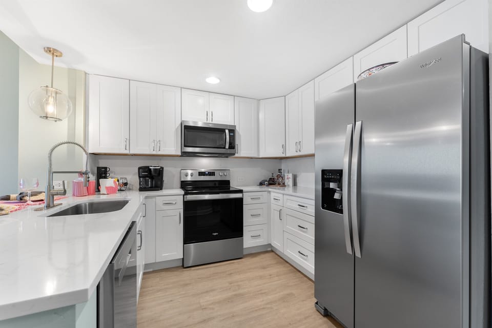 Your fully equipped kitchen features gleaming stainless appliances, crisp white cabinets, and quartz countertops perfect for preparing memorable meals together.