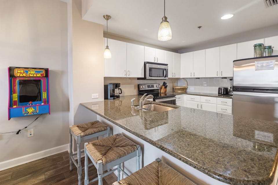 Your fully equipped kitchen awaits with granite counters, stainless appliances, and a fun arcade game for entertainment.