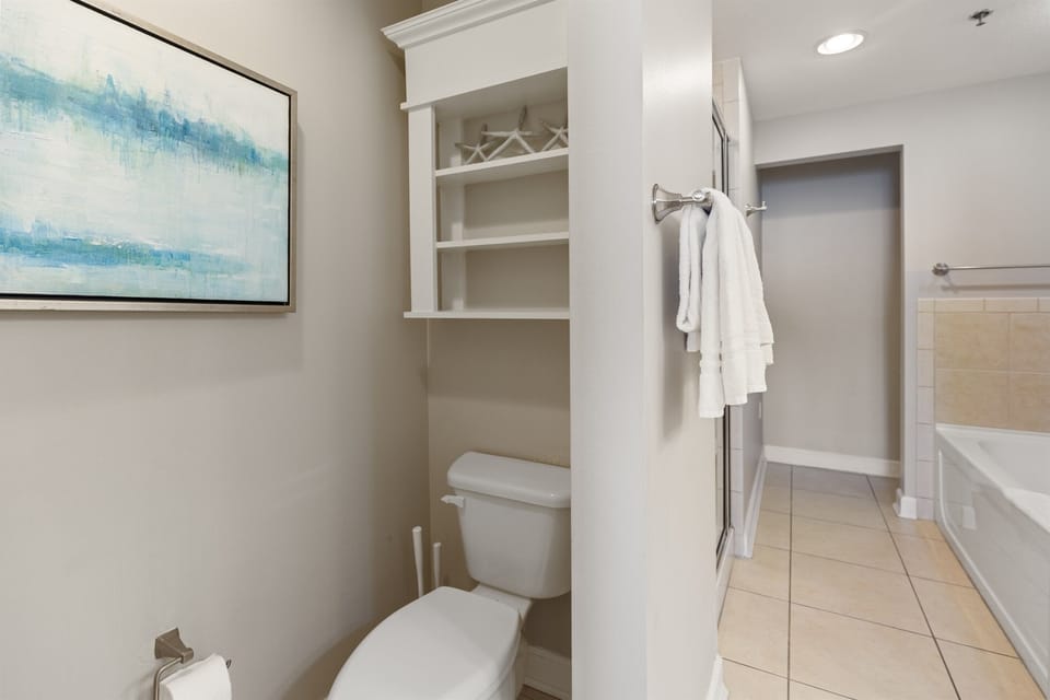 Step into your pristine private bathroom with spacious built-in storage, soft towels ready for your comfort, and elegant coastal-inspired artwork.