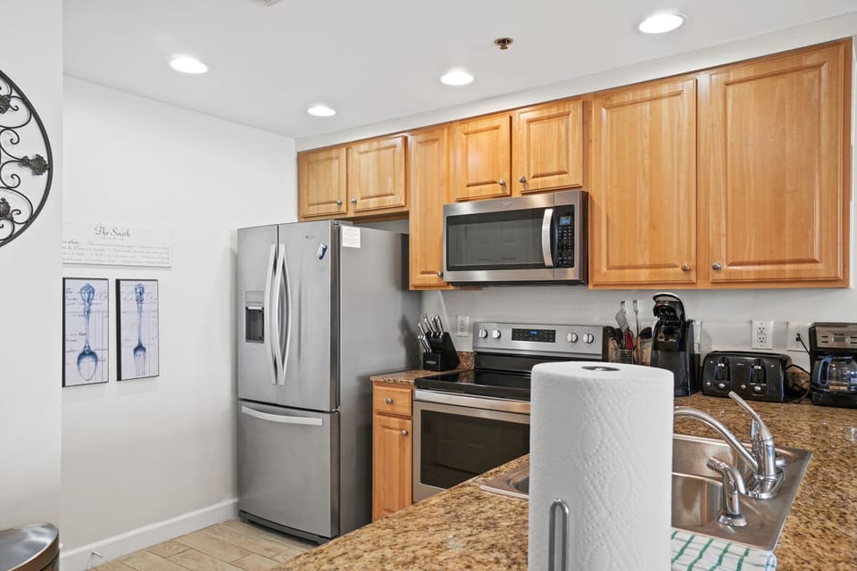 Your fully-equipped kitchen features granite countertops, stainless steel appliances, and warm wood cabinetry perfect for preparing meals.