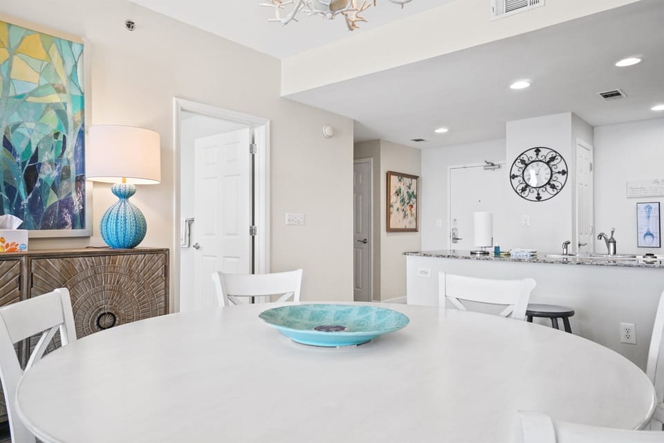 Gather around your stylish dining table in this bright, open-concept space where turquoise accents and coastal art create a serene atmosphere perfect for morning coffee or evening meals.