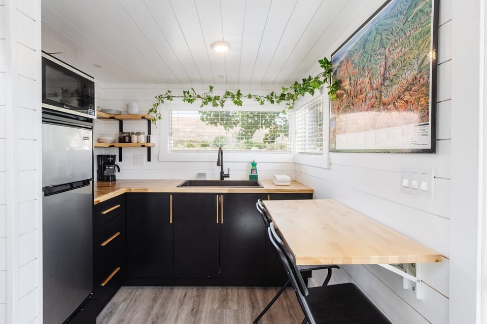The kitchen is fully equipped with a refrigerator, freezer, microwave, cooktop, and sink with hot/cold water. Enjoy coffee from the coffee maker and ample counter space. Essentials include cookware, dishes, utensils, and plenty of storage cabinets.
