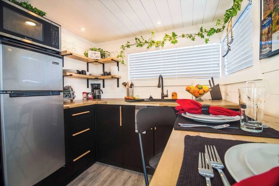 The kitchen is fully equipped with a refrigerator, freezer, microwave, cooktop, and sink with hot/cold water. Enjoy coffee from the coffee maker and ample counter space. Essentials include cookware, dishes, utensils, and plenty of storage cabinets.