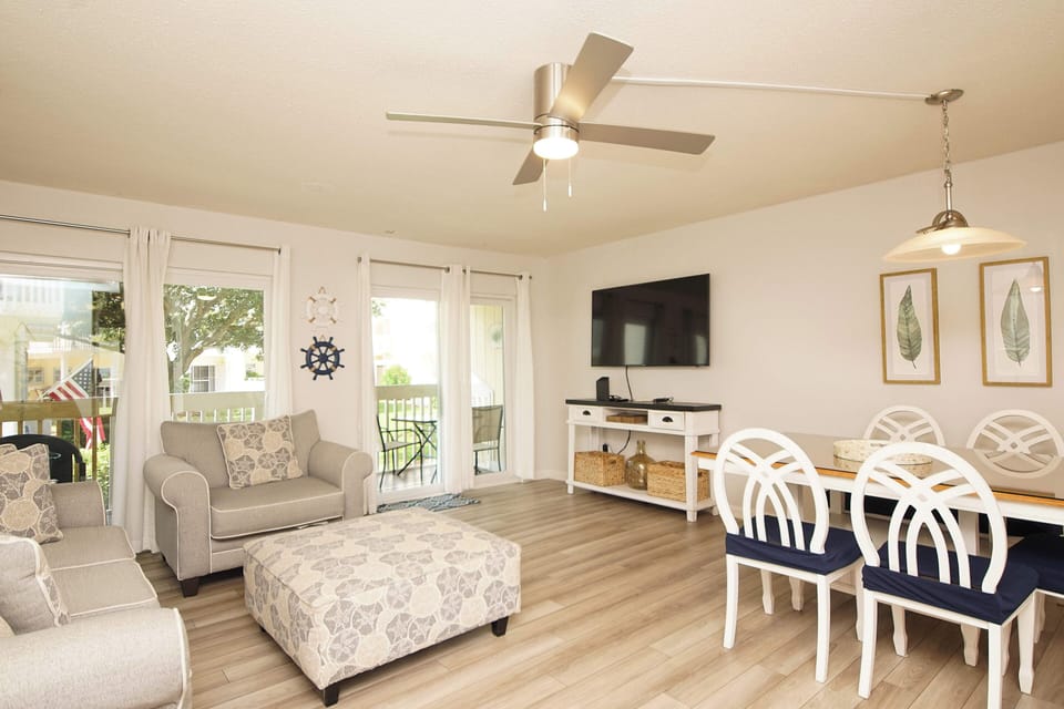 Relax in your bright, airy living space featuring comfortable seating, modern entertainment center, and elegant dining area with coastal-inspired decor.
