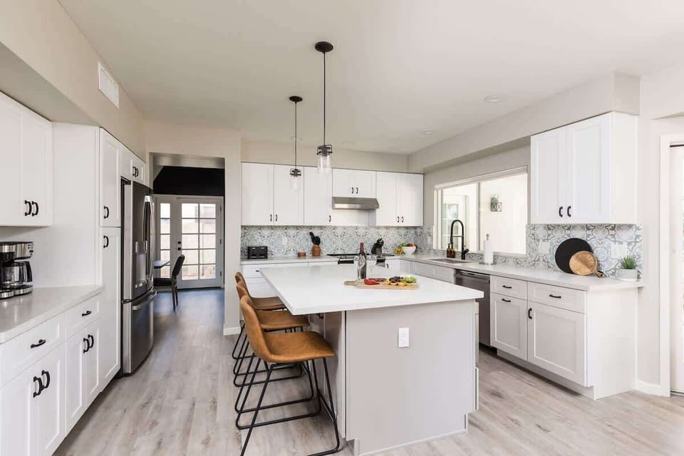 Fully equipped kitchen with stainless steel appliances, kitchen island with bar seating and dining area with seating for 4 guests.
