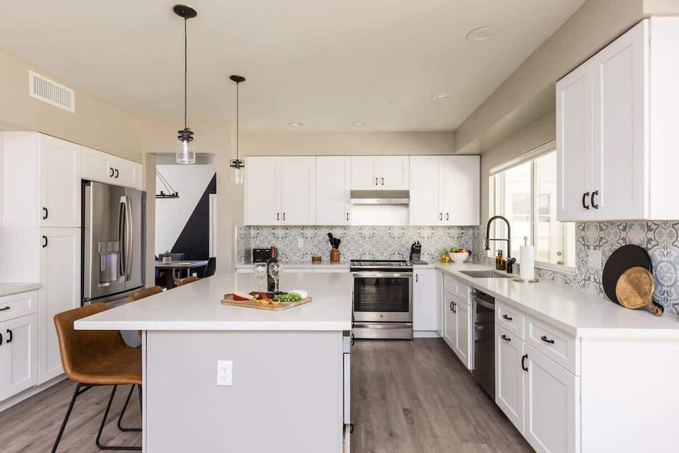 Fully equipped kitchen with stainless steel appliances, kitchen island with bar seating and dining area with seating for 4 guests.