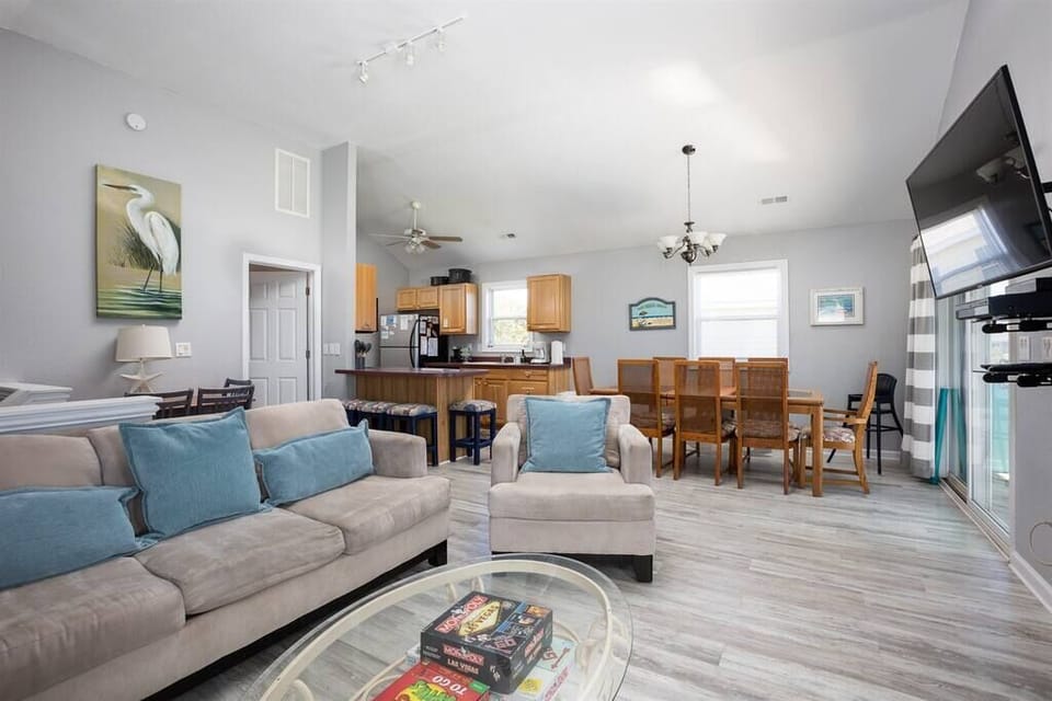 Top Level: Living Area with TV, Cozy Seating, Well-Stocked Kitchen, Breakfast Bar Seating, and Dining Area.