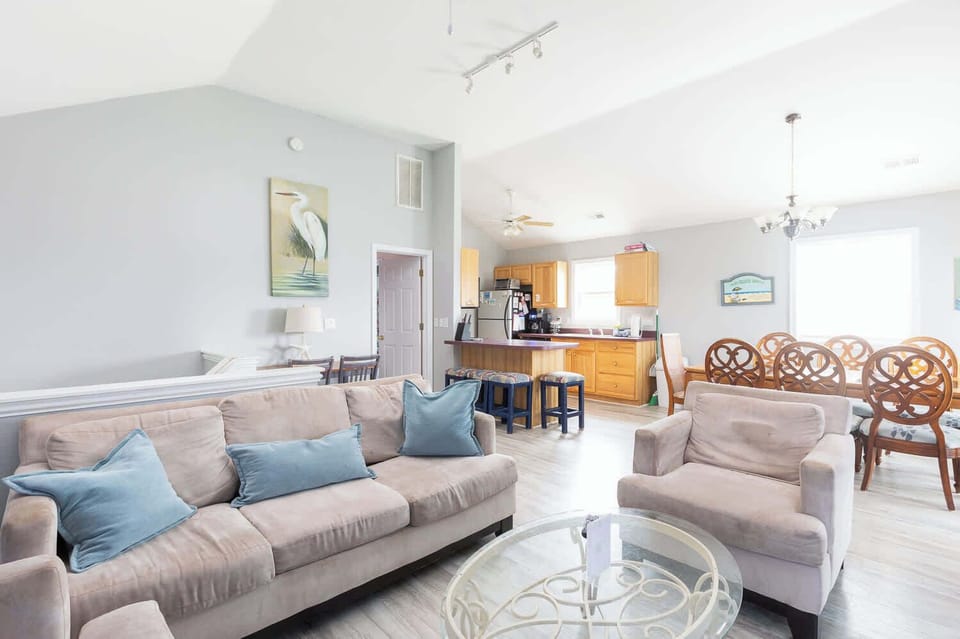 Top Level: Living Area with TV, Cozy Seating, Well-Stocked Kitchen, Breakfast Bar Seating, and Dining Area.