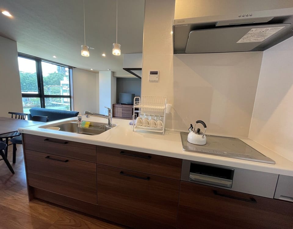 The bright kitchen is equipped with tableware and pots, as well as a refrigerator and microwave.
