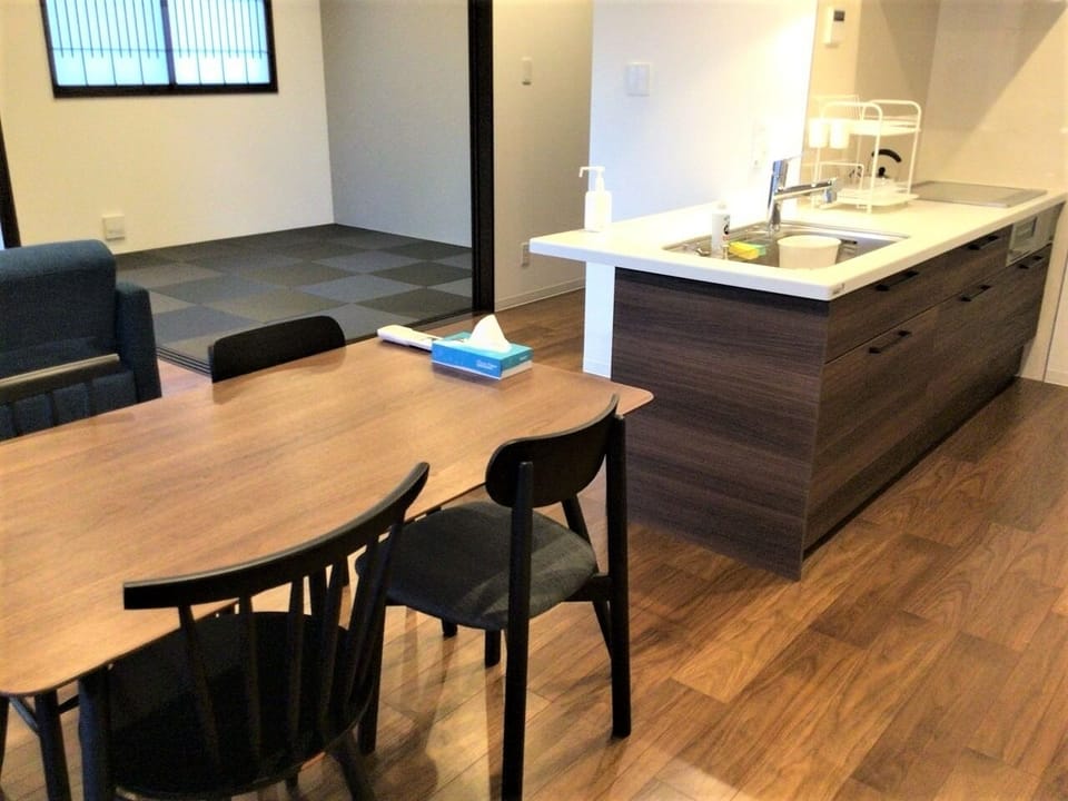 The bright kitchen is equipped with an induction stove, microwave, refrigerator, rice cooker, dishes, and pots and pans.