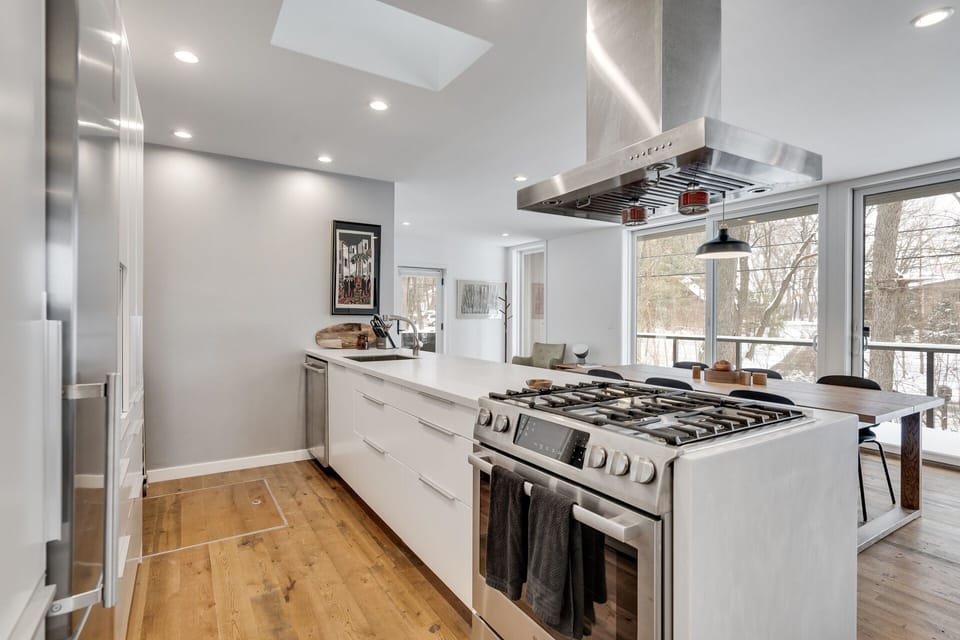 Your gourmet kitchen features premium stainless steel appliances, sleek white counters, and a stunning gas range perfect for cooking memorable meals together.