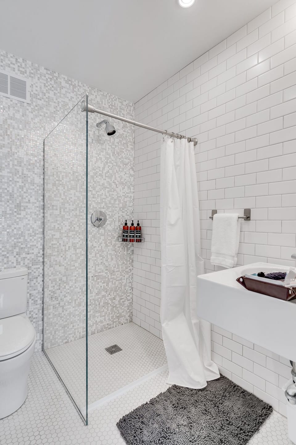 Step into your spa-like bathroom with a spacious walk-in shower, elegant mosaic tiles, and plush towels awaiting your arrival.
