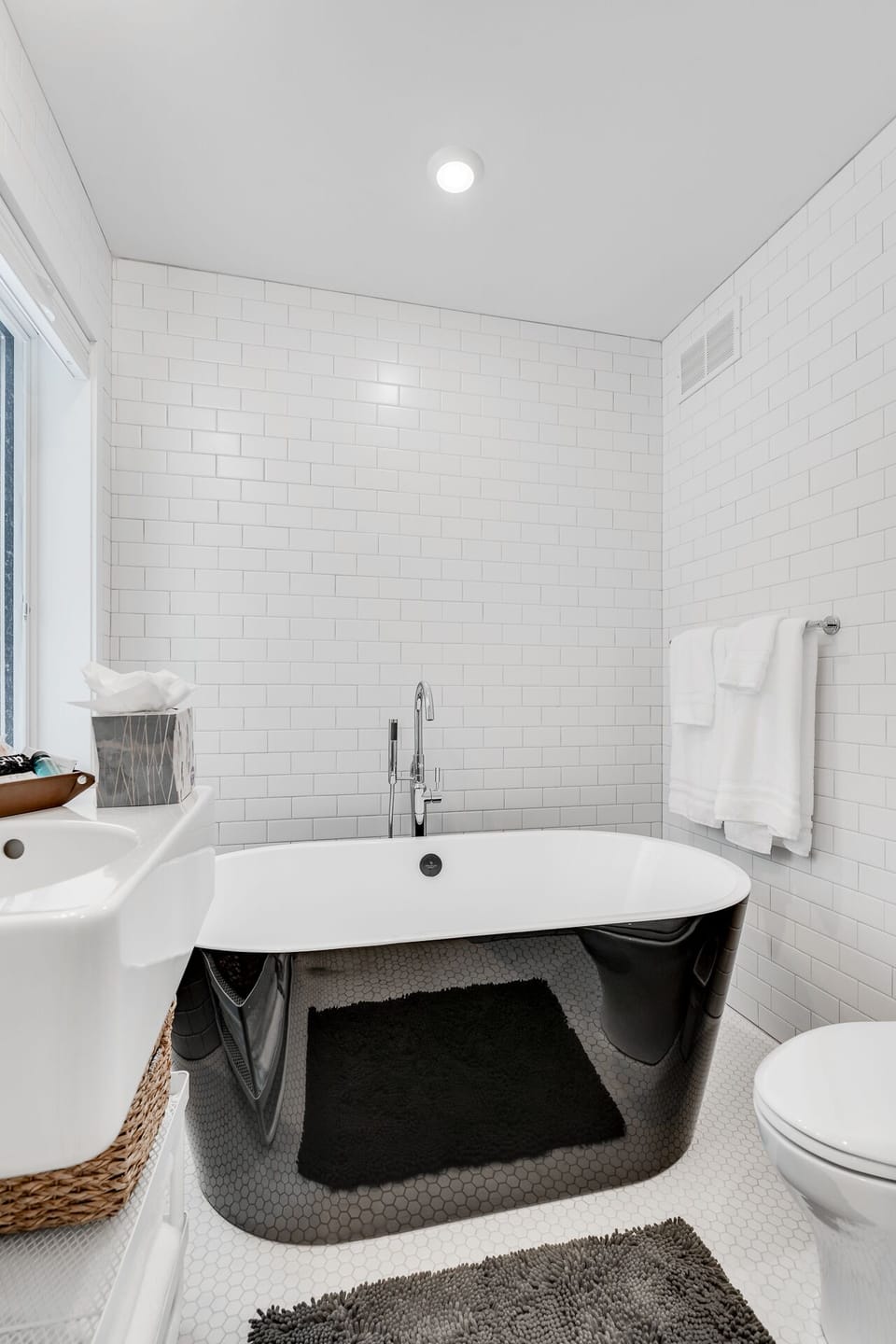 Sink into this elegant freestanding tub surrounded by crisp white subway tiles, where fluffy towels await your relaxing soak.