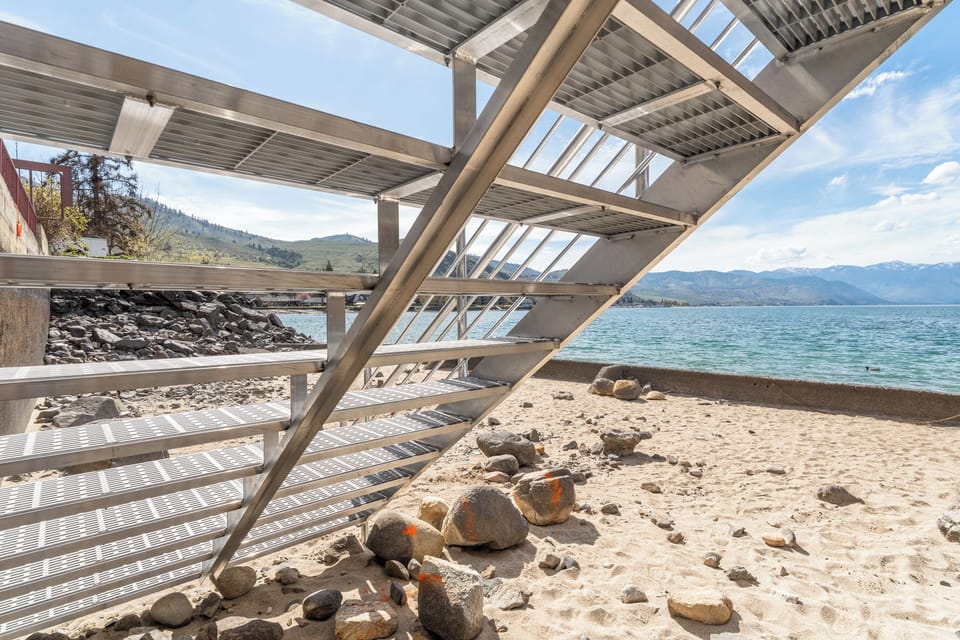 Lakefront location features sandy beach access with scenic mountain backdrop and crystal-clear waters for peaceful waterside relaxation.