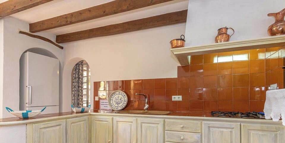 Side view of the rustic kitchen with wooden furniture, spacious countertops and full equipment for everyday use.