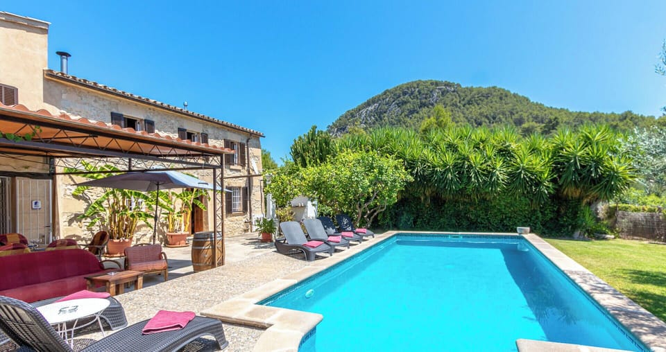 View of the private swimming pool with sunbathing area, garden and natural surroundings with mountain views.
