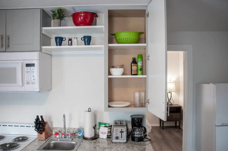Open kitchen and living area with white cabinetry and organized storage.